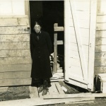 Woman standing in a barracks doorway at Tanforan Assembly Center