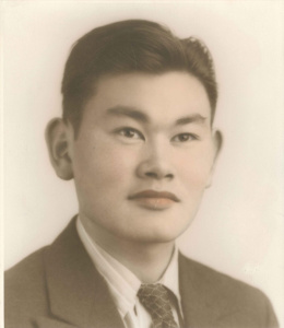 Photo of young Korematsu. He has medium hair and is wearing a suit. 