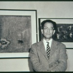 Man standing in front of two framed paintings