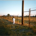 Former camp inmate next to a barbed wire fence